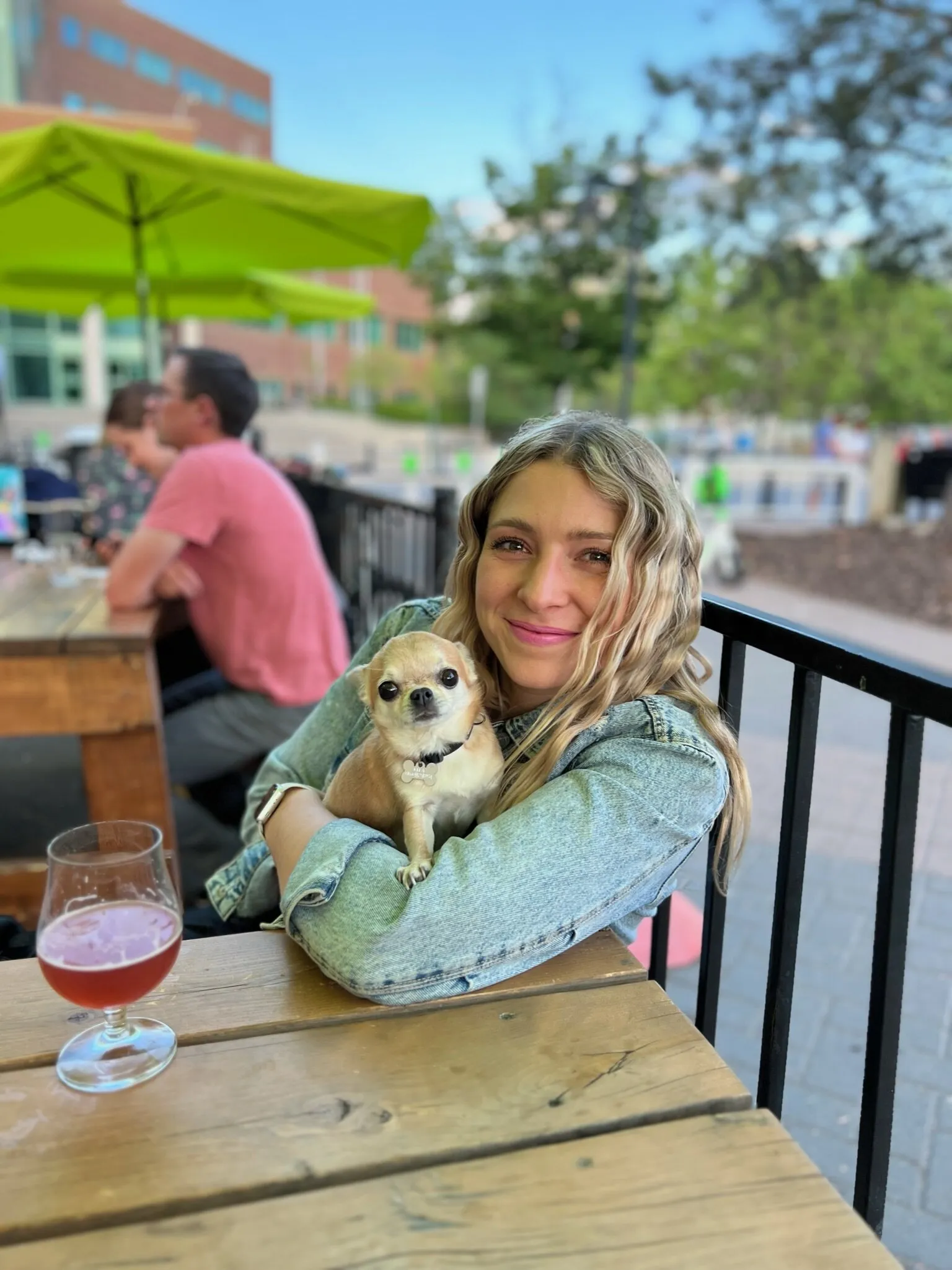Katerina Kaslova smiling at an outdoor patio table, holding her chihuahua